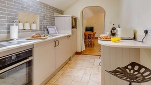 Eine Küche mit eingebautem Geschirrspüler, einem Fenster über der Spüle und einem Essbereich mit Tisch und Stühlen.