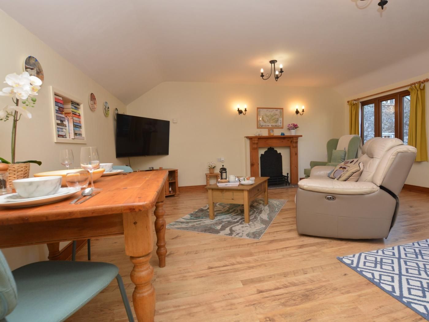 Una sala de estar con una mesa de comedor de madera, un sofá, una chimenea y un televisor.