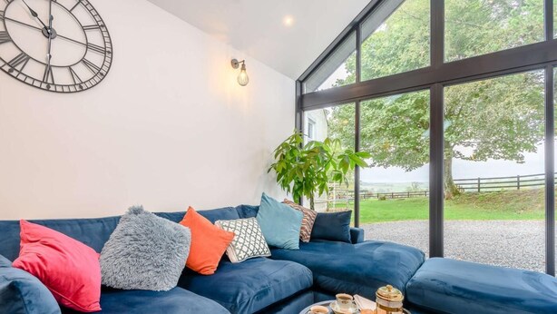 Una sala moderna con un sofá azul, un reloj de pared grande y una mesa de centro con un juego de té.