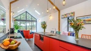 Una cocina moderna con armarios rojos, una isla central y un comedor con sillas coloridas.