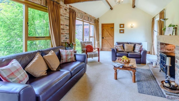 A spacious living room with a leather sofa, a wooden coffee table, and a fireplace. - 3 Bed in York (oc-83264) (High Catton)