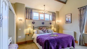 A bedroom with a bed, two bedside lamps, a window with curtains, a radiator, and a small table with a tray. - 3 Bed in York (oc-83264) (High Catton)