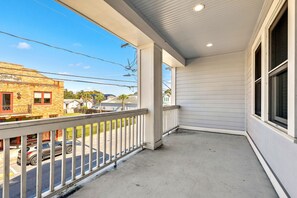 A covered outdoor area with a concrete floor, a white railing, and a view of the street and buildings in the background. - Sleeps 16 | 5BR Ybor Duplex w/ Game Room | 2 Kitchens, 4 Baths & Parking (Tampa)