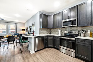 A modern kitchen with dark cabinets, stainless steel appliances, and a breakfast bar. - Sleeps 16 | 5BR Ybor Duplex w/ Game Room | 2 Kitchens, 4 Baths & Parking (Tampa)