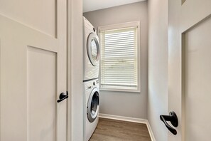 A laundry room with a washing machine and dryer, a window with blinds, and a door with a handle. - Sleeps 16 | 5BR Ybor Duplex w/ Game Room | 2 Kitchens, 4 Baths & Parking (Tampa)
