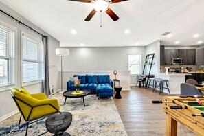 A modern living room with a blue sofa, yellow armchair, and a wooden coffee table. - Sleeps 16 | 5BR Ybor Duplex w/ Game Room | 2 Kitchens, 4 Baths & Parking (Tampa)