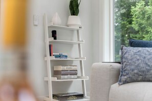 A white bookshelf with books and a 300-piece poker set. - New Construction Designer Home: Private Outdoor Oasis, Hot Tub, Sauna (Eastham)