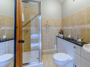 Ein Badezimmer mit einer Glaskabine zur Dusche, einer Toilette und einem Waschbecken.