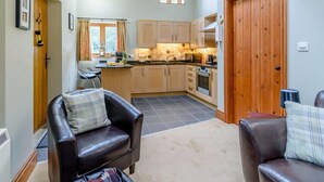 A cozy living room with a fireplace, a dining area, and a kitchen with wooden cabinets and a large window. - 1 Bed in York (oc-83265) (High Catton)