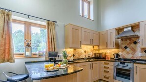 A kitchen with a central island, wooden cabinets, a microwave, a stove, and a window with curtains. - 1 Bed in York (oc-83265) (High Catton)