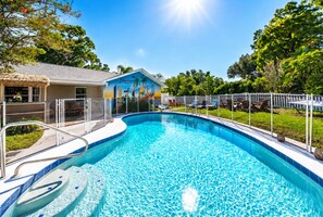 Une piscine à l’eau d’un bleu cristallin, entourée d’une clôture blanche, et un bâtiment orné d’une fresque représentant la Floride.