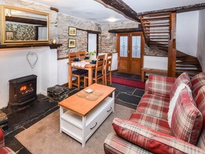 Ein gemütliches Zimmer mit Kamin, Holzmöbeln, einem Karomuster-Sofa und einer Steinwand.