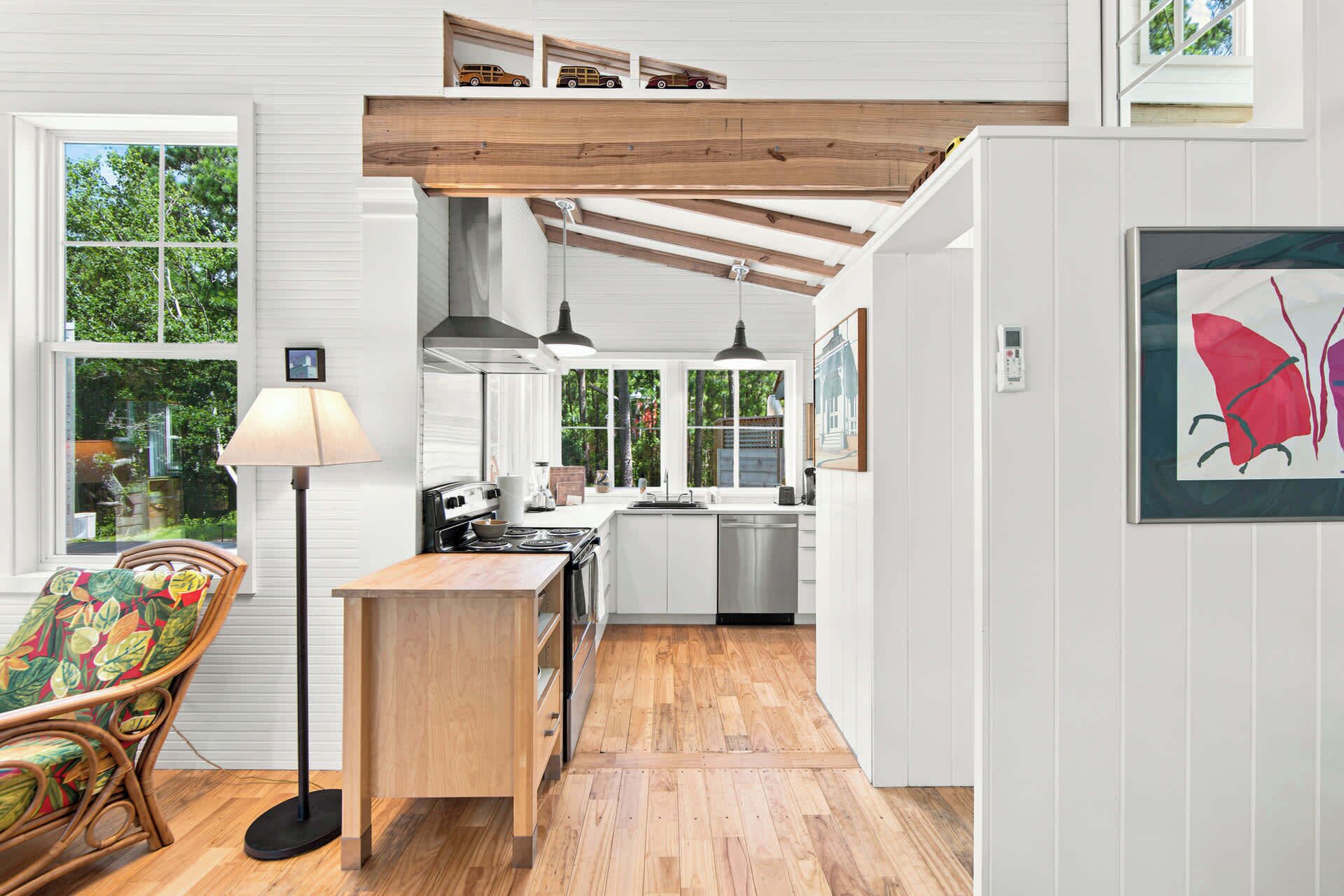 A kitchen with a stove, sink, and wooden ceiling beams.