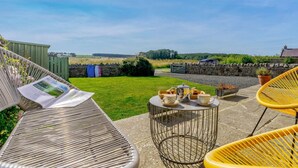 A patio with wicker furniture, a table with cups and a kettle, and a view of the countryside. - 4 Bed in Belford (oc-83373) (Belford)