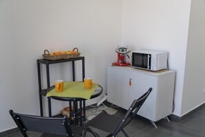 A small kitchenette with a microwave, a table with two yellow mugs, a wicker basket with oranges, and a black chair. - Villa Quattro Lune - Partinico (Partinico)