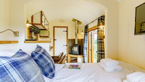 Ett hotellrum med en säng, en stol, en tv och en spegel.
