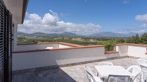 A terrace with a view of distant mountains, white outdoor furniture, and a tiled floor. - Camera Luna Perla - Partinico (Monreale)