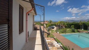 Un balcón con vistas a una piscina y el paisaje circundante.