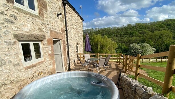 A stone building with a hot tub, outdoor seating, and a view of a forested hill. - 2 Bed in Matlock (oc-83435) (Slaley)