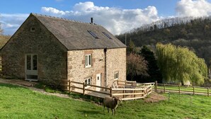 A stone building with a sloped roof, a small porch, and a fenced outdoor area. - 2 Bed in Matlock (oc-83435) (Slaley)