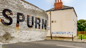 Un letrero desgastado con el nombre 'SPURN' en un poste de madera.