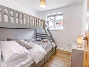 Ein Etagenbett mit einer Leiter, ein Nachttisch mit Lampe und ein Fenster mit Blick ins Freie.