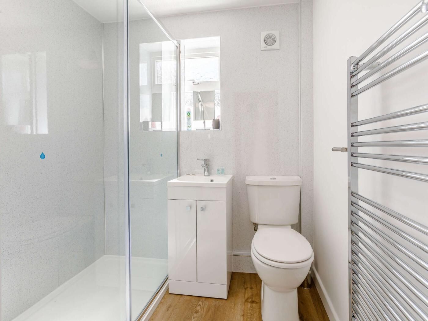 A modern bathroom with a glass shower enclosure, a white toilet, and a built-in sink.
