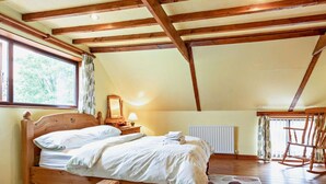 Un dormitorio con una cama de madera, un radiador, un sillón mecedora y una ventana con cortinas.