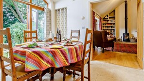 A dining area with a table set for four, chairs, a bookshelf, and a fireplace. - 3 Bed in Holt (oc-83628) (Blakeney)