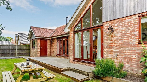 A brick house with a patio, a wooden table, and a garden. - 3 Bed in Holt (oc-83628) (Blakeney)