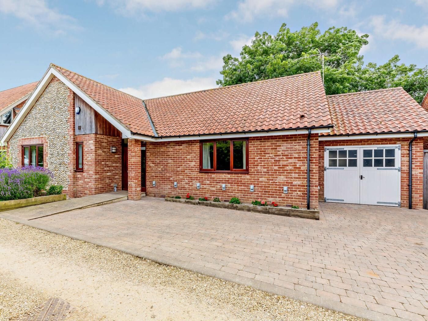 A two-story brick house with a tiled roof, a garage, and a front garden.