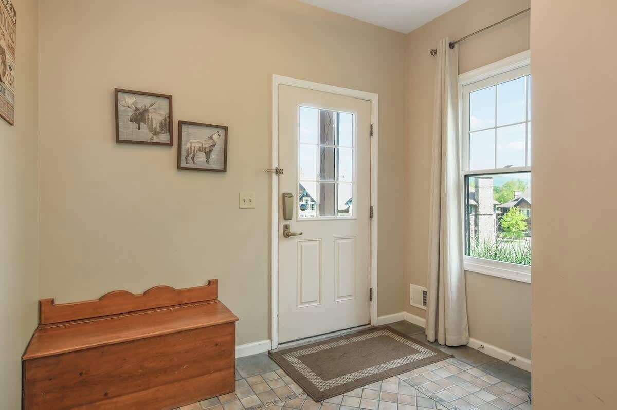 A hallway with a white door, a bench, and two framed pictures on the wall.