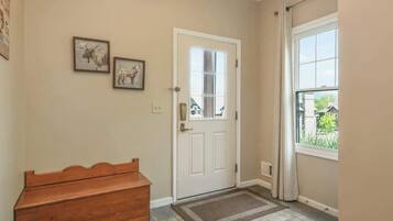 A hallway with a white door, a bench, and two framed pictures on the wall.