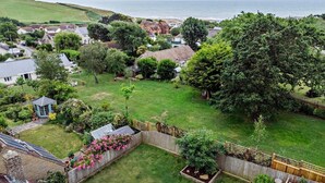 A residential area with houses, a large tree, and a view of the sea. - 5 Bed in Bridport (oc-83584) (Charmouth)