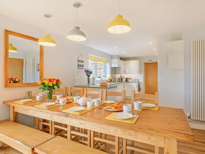 A dining area with a wooden table set for four, a mirror, and pendant lights.