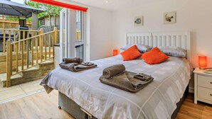 A bedroom with a bed, pillows, a nightstand, a window, and a view of an outdoor patio. - 5 Bed in Bridport (oc-83584) (Charmouth)