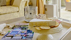 A table with a cheese platter, a magazine, and a candle in a room with a sofa and a window. - 2 Bed in Halifax (oc-83521) (Halifax)