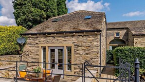 A stone building with a tiled roof, a gated patio area with outdoor furniture, and a satellite dish. - 2 Bed in Halifax (oc-83521) (Halifax)