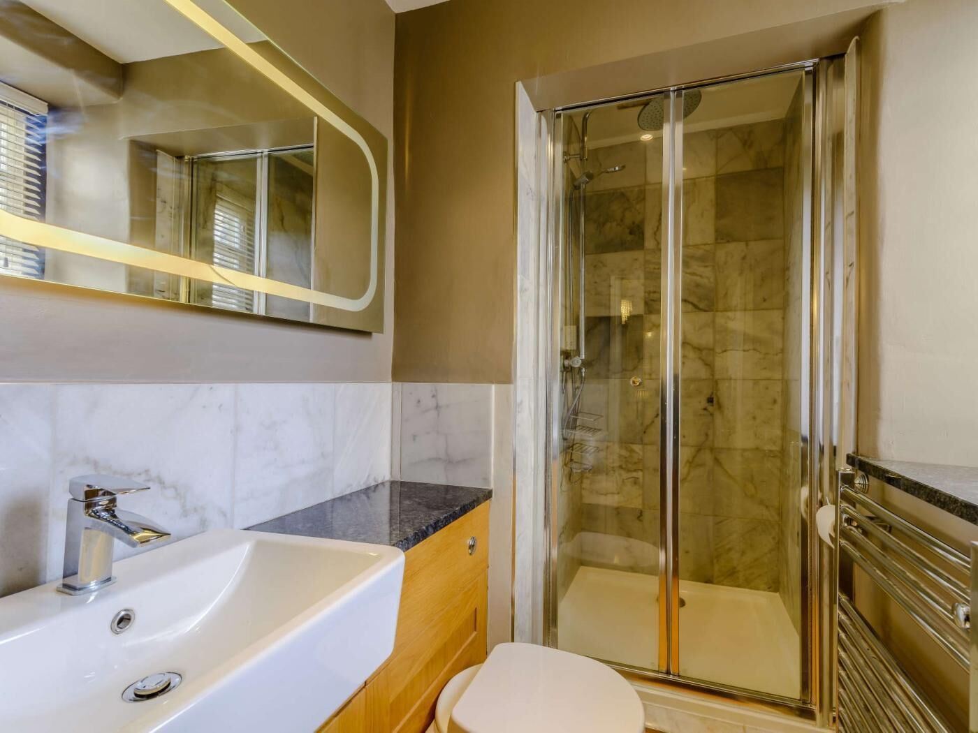 Et badeværelse med badekar, toilet, brusekabine med glasvægge og et spejl.