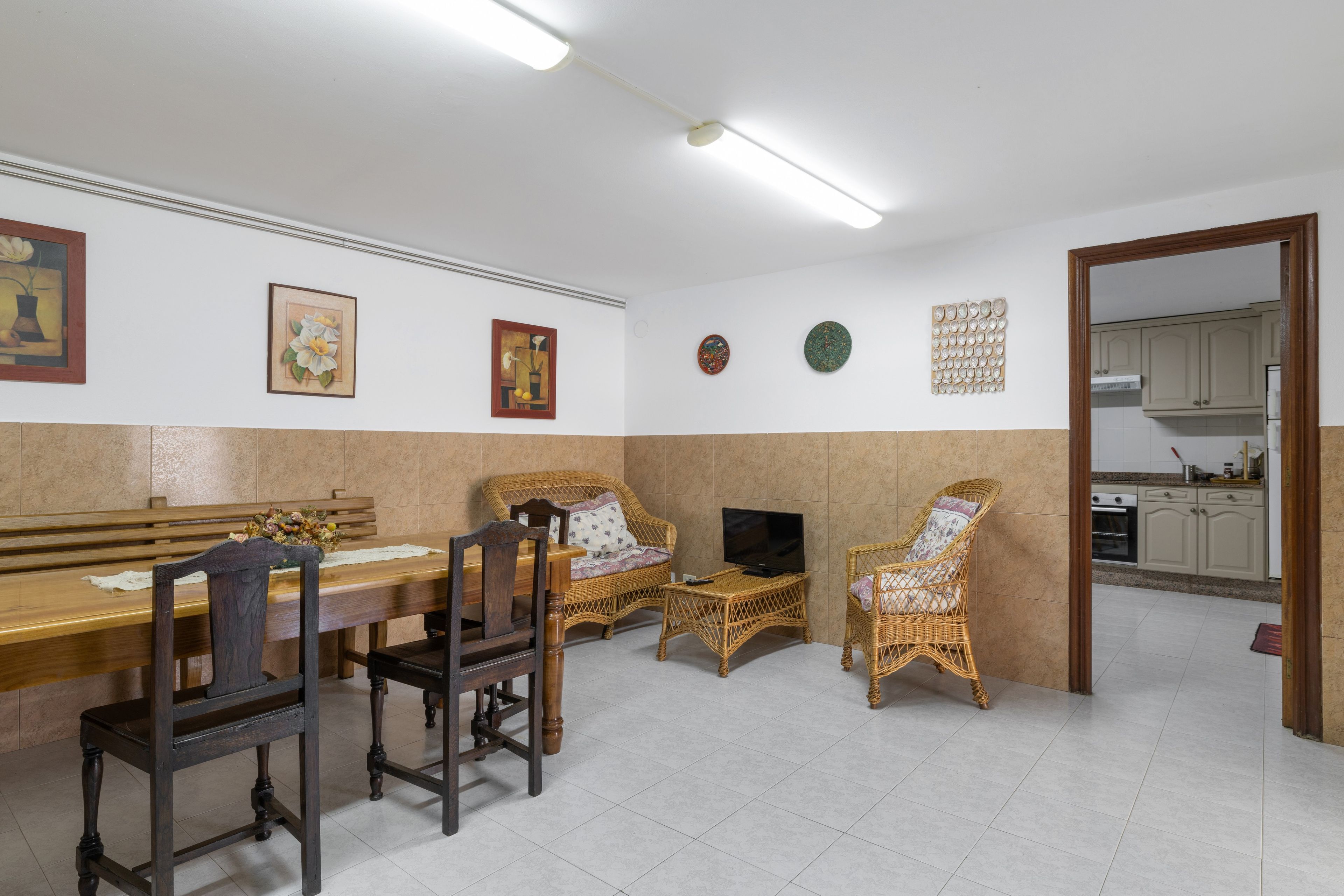 Un comedor con una mesa de madera, sillas y un televisor.