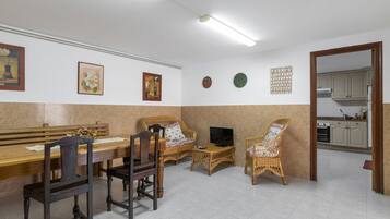 Un comedor con una mesa de madera, sillas y un televisor.