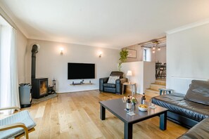 A modern living room with a fireplace, a flat-screen TV, a sofa, a coffee table, and a dining area with chairs.