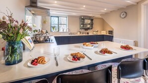 A modern kitchen with a central island, a dining area with chairs, and a clock on the wall.