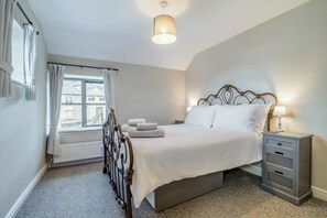 Un dormitorio con cama, mesita de noche, lámpara y vistas al exterior.