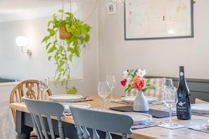 A dining table set with plates, glasses, and a bottle of wine.