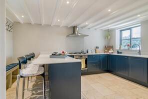 A modern kitchen with a central island, bar stools, a stove, and a large window.