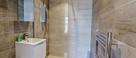 A modern bathroom with a glass-enclosed shower, a white sink, and a mirror.