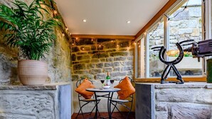 A stone-walled room with a table and chairs, a potted plant, and a wine bottle. - 2 Bed in Morpeth (oc-83597) (Rothbury)
