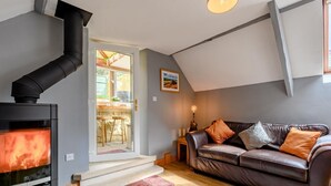 A cozy living room with a fireplace, a leather sofa, and a dining area visible through an open door. - 2 Bed in Morpeth (oc-83597) (Rothbury)