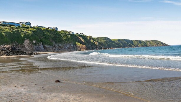 A coastal beach with a curved shoreline, cliffs, and houses on the hillside. - 3 Bed in St. Austell (oc-83541) (Gorran Haven)